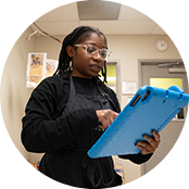 A child care worker uses an electronic tablet with a blue case to review daily reports for their preschool students. 